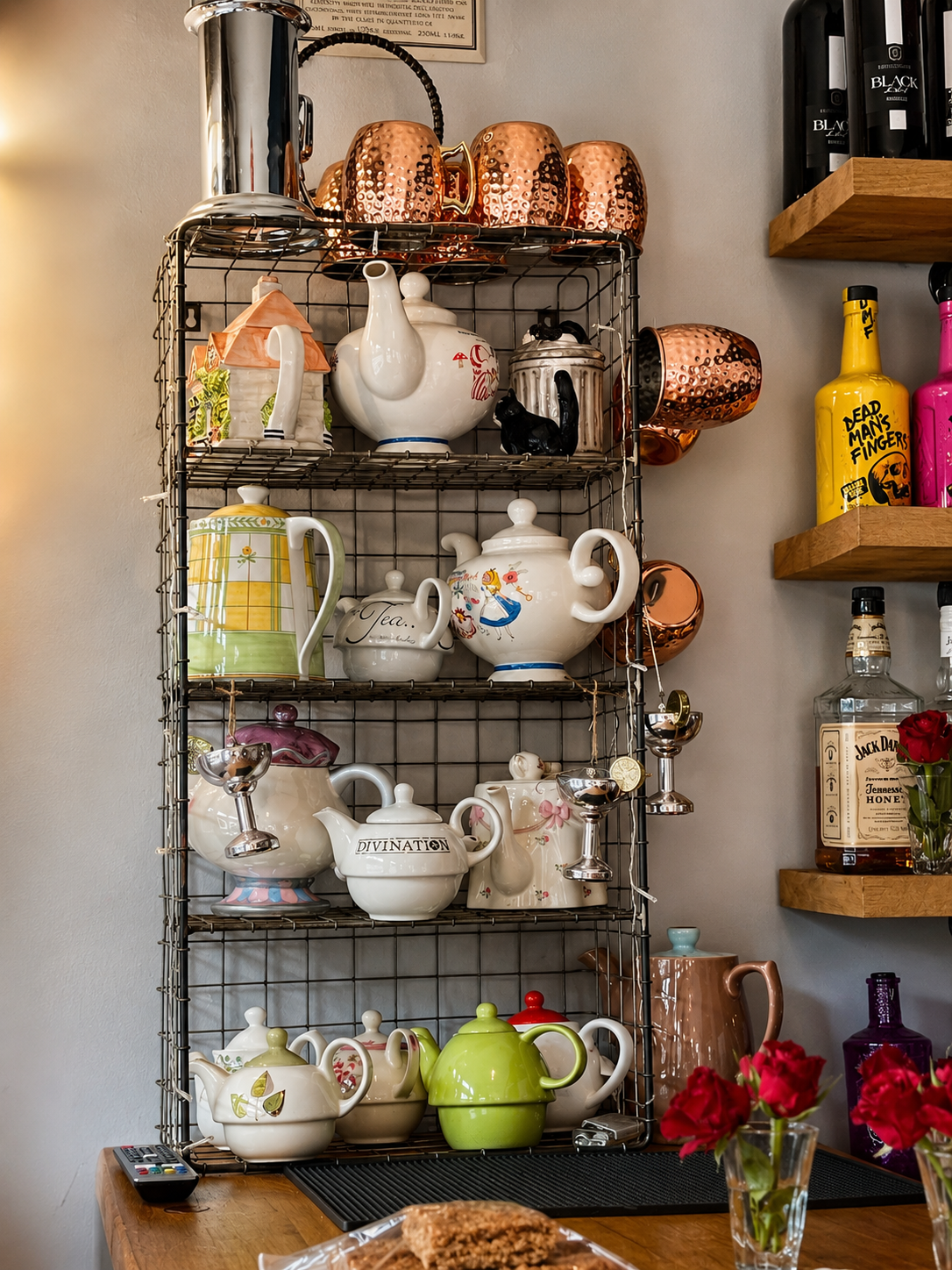 A colourful teaware display beside bottles and flowers